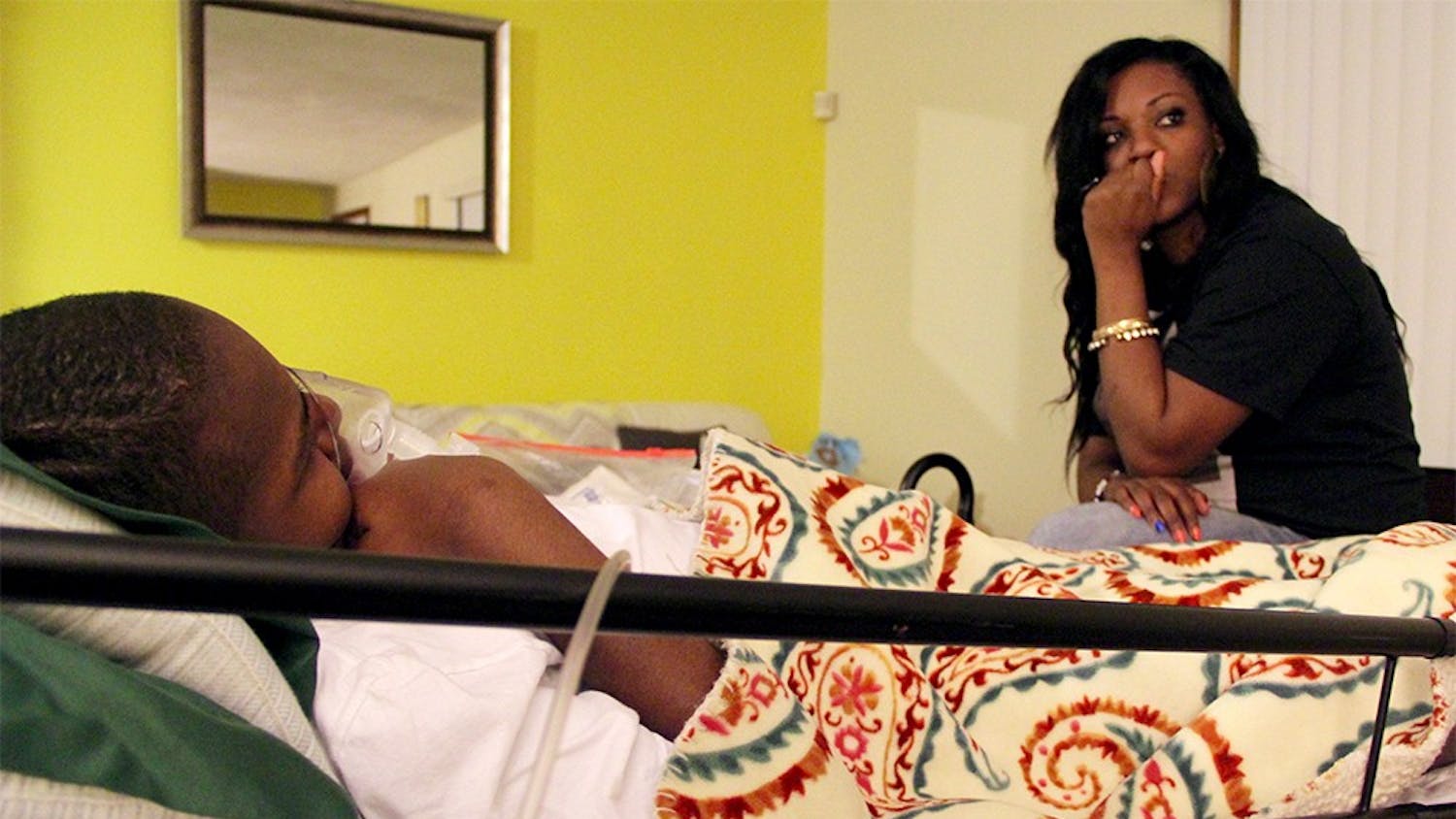 DeAndra Yates sits on her son's hospital bed on Mar. 5 at their home in Indianapolis. Her son, Dre Knox, was shot in the head in 2014 when he was 13 years old. Since then, he hasn't been able to walk ot talk. Over the past two years, DeAndra has become a vocal advocate against gun violence.