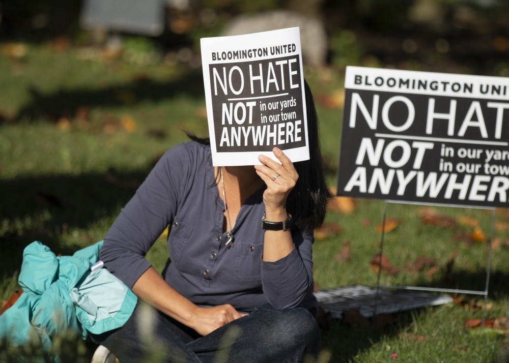<p>A woman covers her face from the sun with a Bloomington United program Aug. 27, during a solidarity event at the Monroe County Courthouse. The event featured several speakers who talked about their experience with racism and hate and how to overcome it. </p>