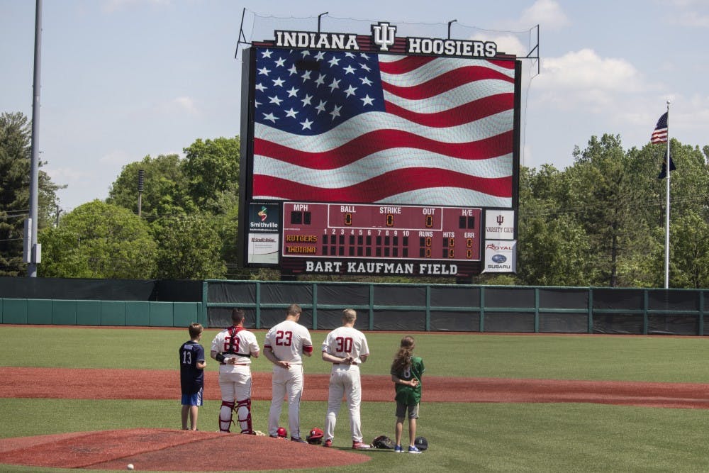 <p>Senior catcher Ryan Fineman, junior left-handed pitcher Andrew Saalfrank and junior infielder Scotty Bradley stand with two children on the pitching mound May 18 at Bart Kaufman Field. Players stood for the national anthem before playing Rutgers.</p>