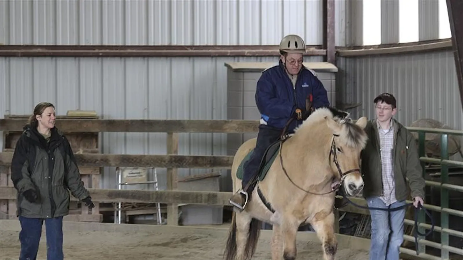 Trainer Jennifer Lung watches as Steve McGovern and his horse are guided by Ben Slinkard Tuesday afternoon at the PALS arena. McGovern is 43 years old and has been riding at People and Animal Learning Services for five years.