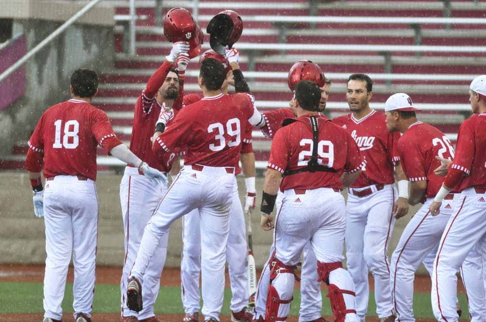 IU players meet senior outfielder Craig Dedelow at home plate after he hit a grand slam in the seventh inning of a game against Maryland on Sunday. IU won 6-3.