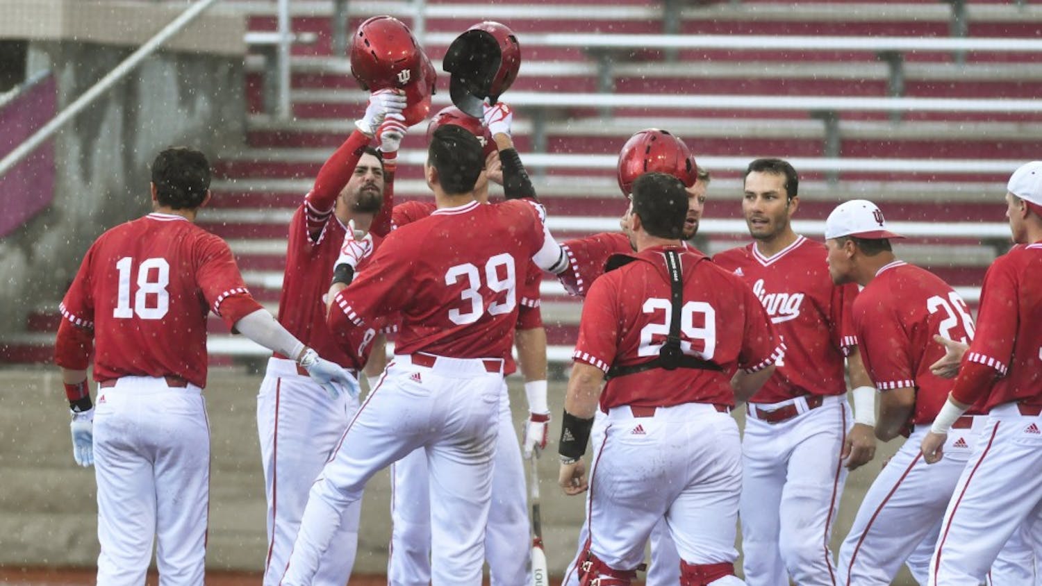 IU players meet senior outfielder Craig Dedelow at home plate after he hit a grand slam in the seventh inning of a game against Maryland on Sunday. IU won 6-3.