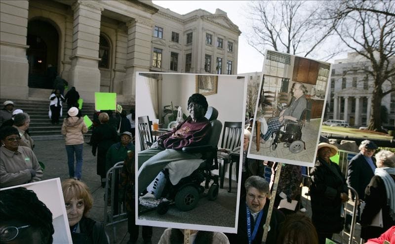 Demonstrators hold signs including photos of the elderly who need care, to protest the governor's plans to reduce funding for senior services, outside the Georgia capital Thursday in Atlanta. Advocates estimate that the cuts to elderly nutrition programs will mean the loss of 138,000 meals from the roughly 3.9 million delivered to homes or provided through senior centers.
