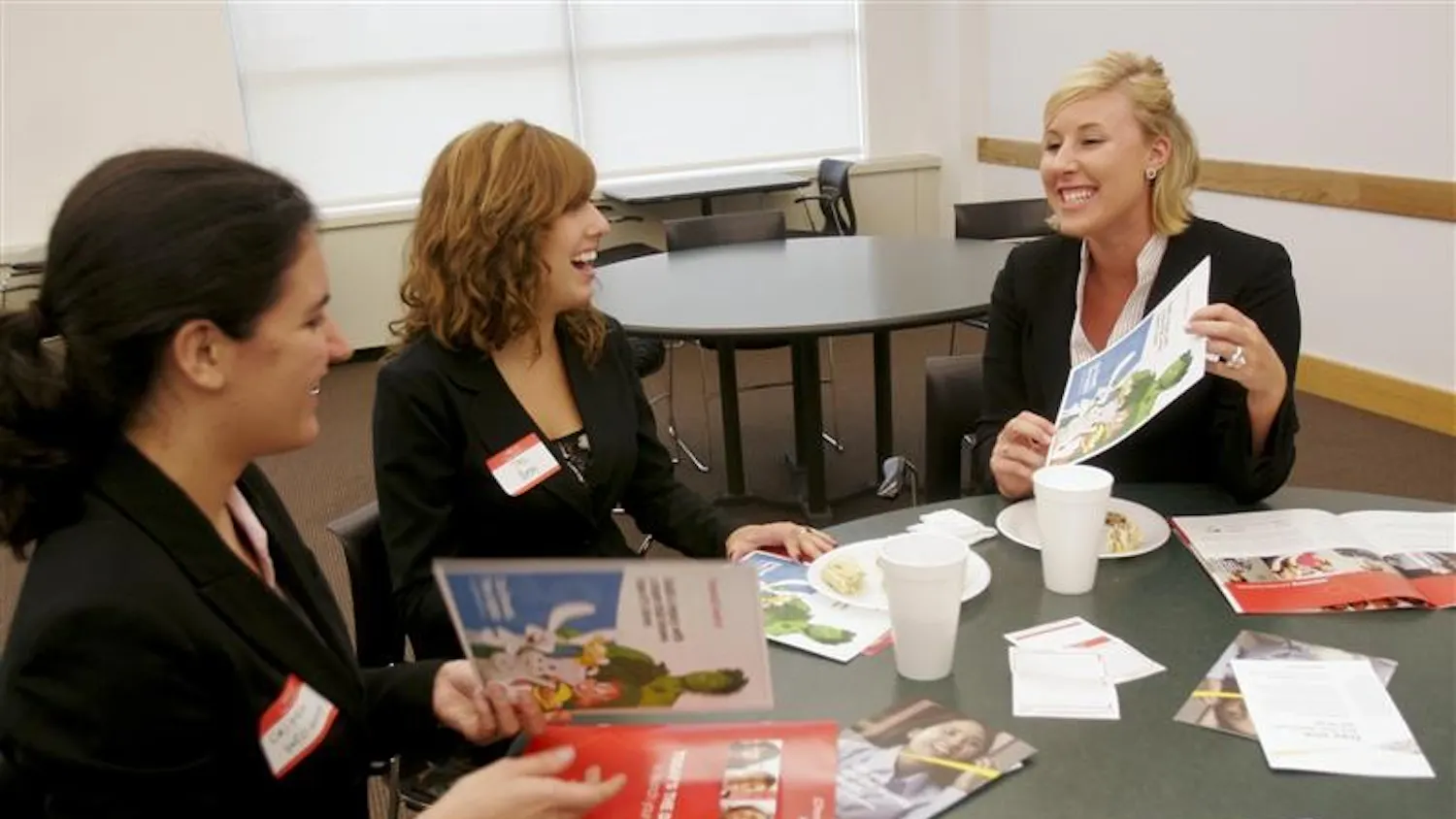 Freshmen Caitlin Williams, Tess Bedel, and Lindsay Edwards look through pamphlets that were give out by various companies at an event sponsored by the Undergraduate Black MBA Association Tuesday evening at the Kelley School of Business. The corporate networking fair brought together campus represenatives from companies such as General Mills, Target, and Ernst & Young.