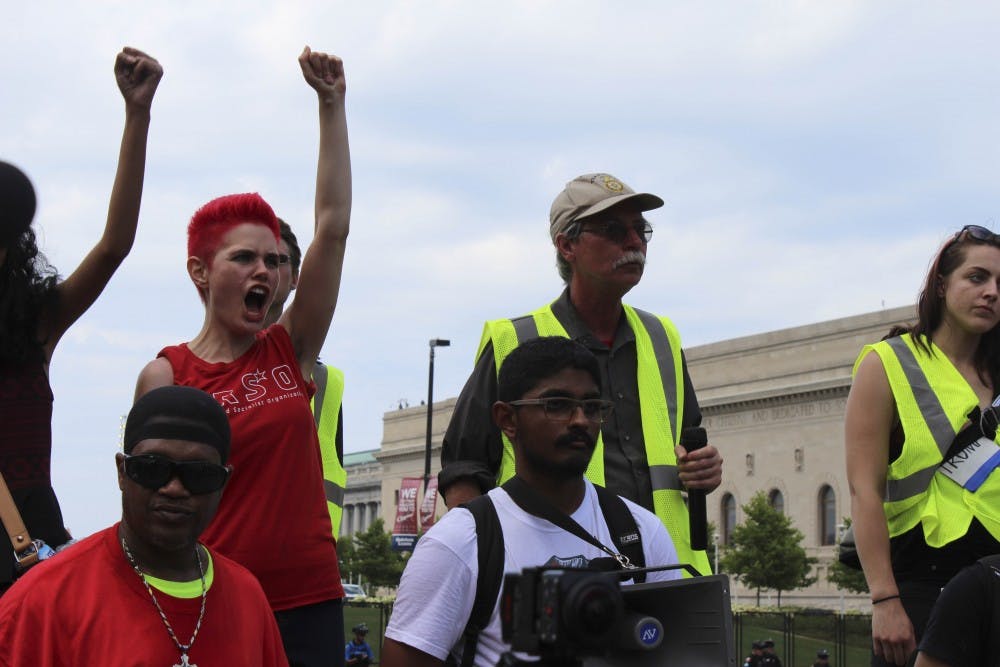 Kait McIntyre and other demonstrators raise their fists in the air, calling for equality for all in America.