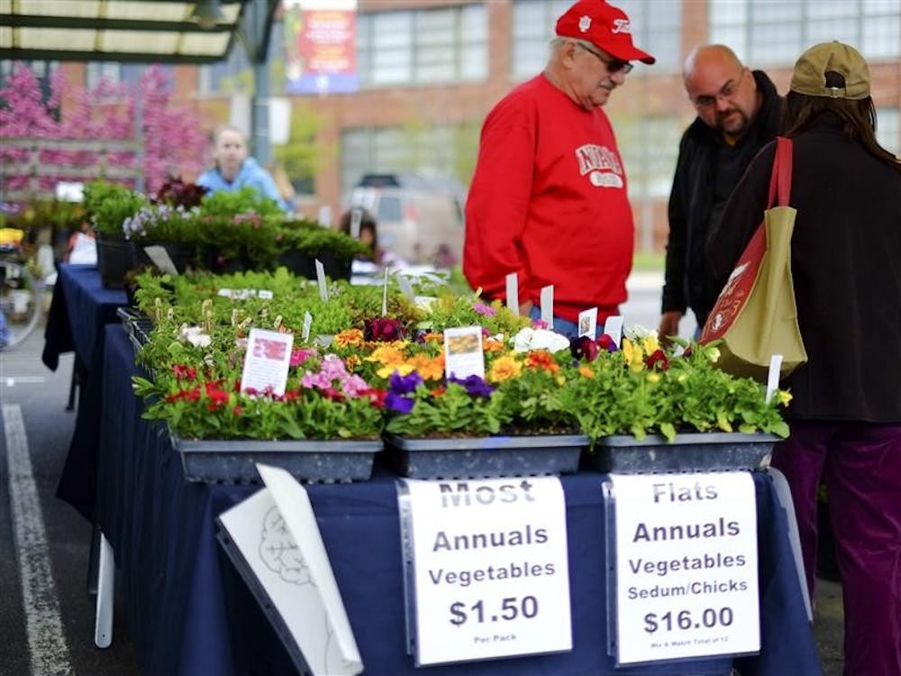 Colorful flowers and fresh vegetables are displayed at a booth Saturday at the Bloomington Farmer's Market outside of City Hall. 