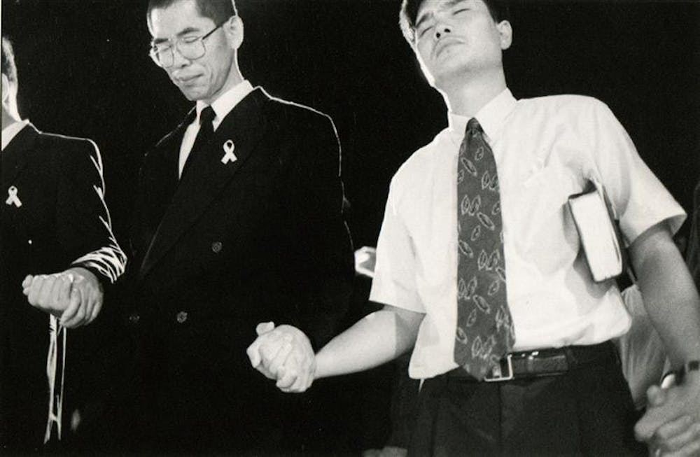 Mourners outside the Korean United Methodist Church hold hands July 14, 1999, in a prayer for Won-Joon Yoon and the reconsecration of the church.