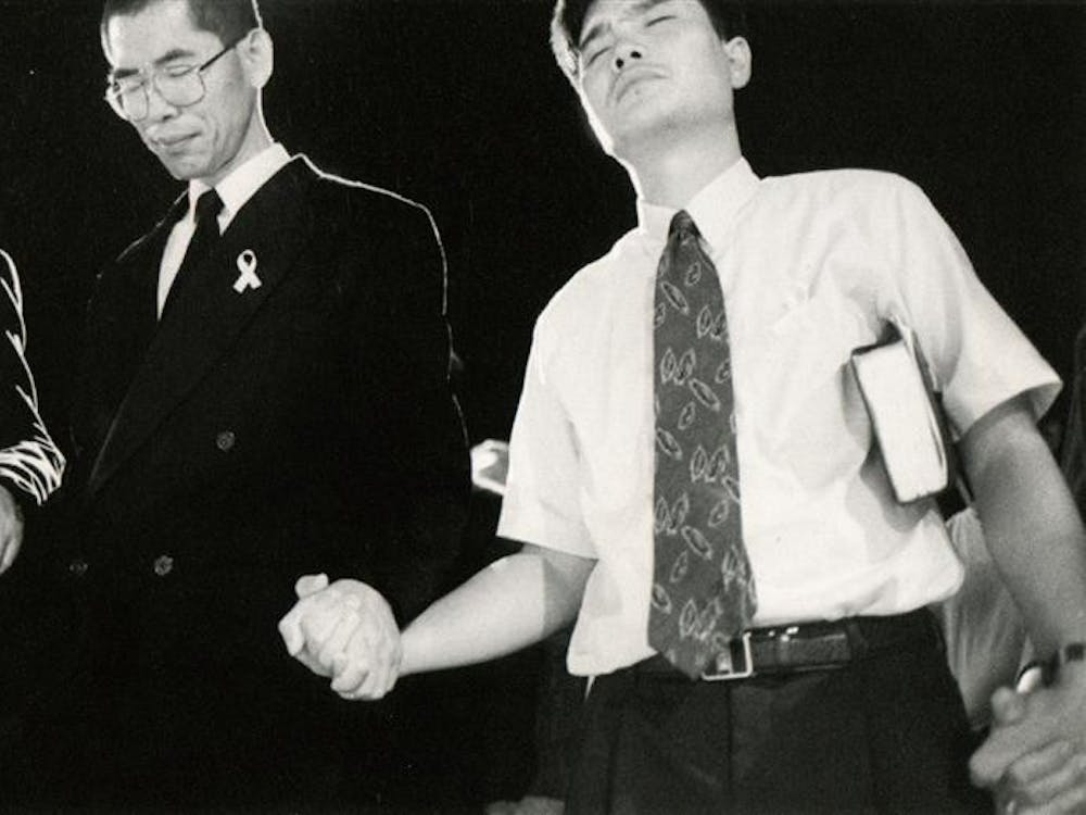 Mourners outside the Korean United Methodist Church hold hands July 14, 1999, in a prayer for Won-Joon Yoon and the reconsecration of the church.