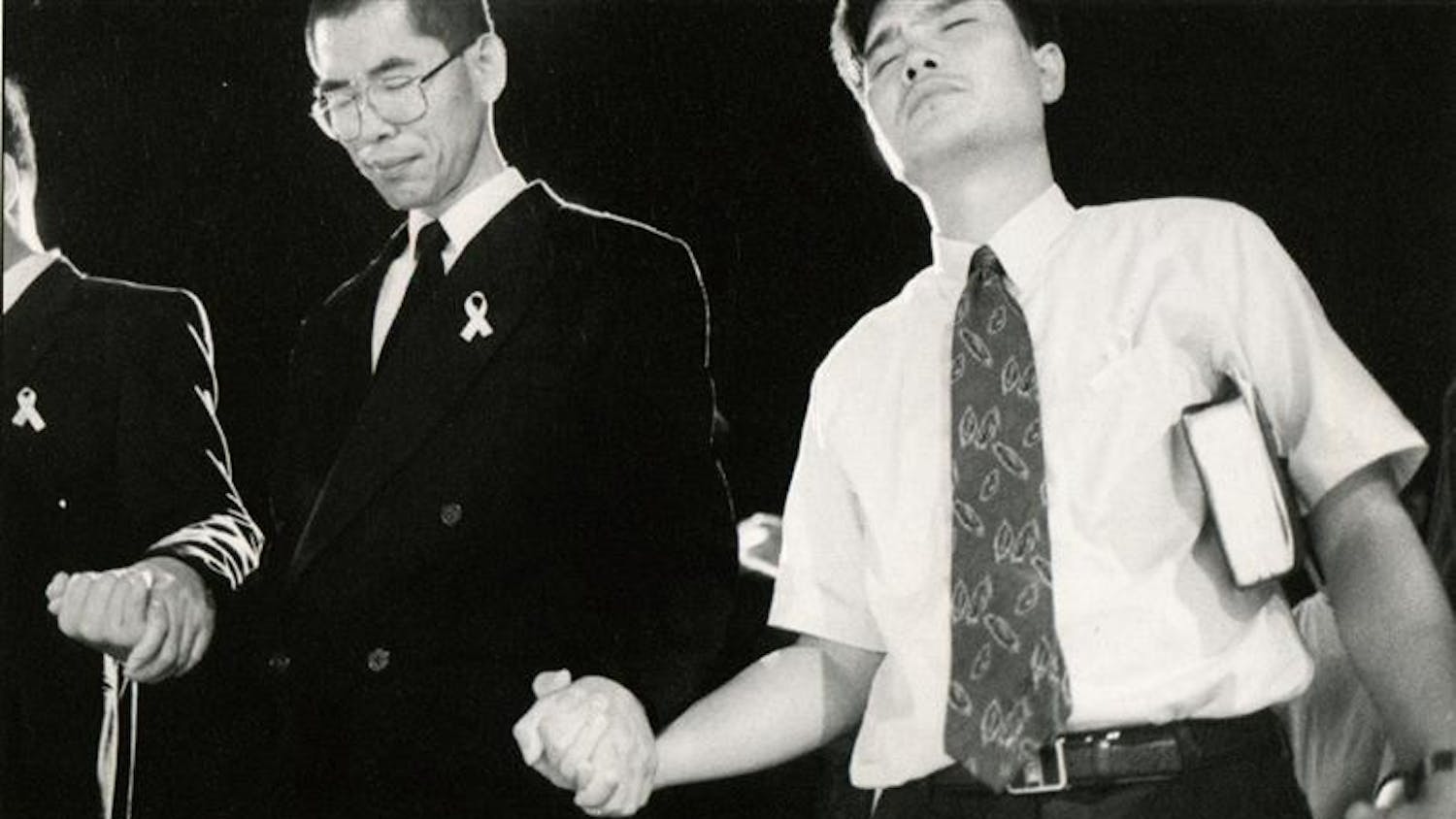 Mourners outside the Korean United Methodist Church hold hands July 14, 1999, in a prayer for Won-Joon Yoon and the reconsecration of the church.