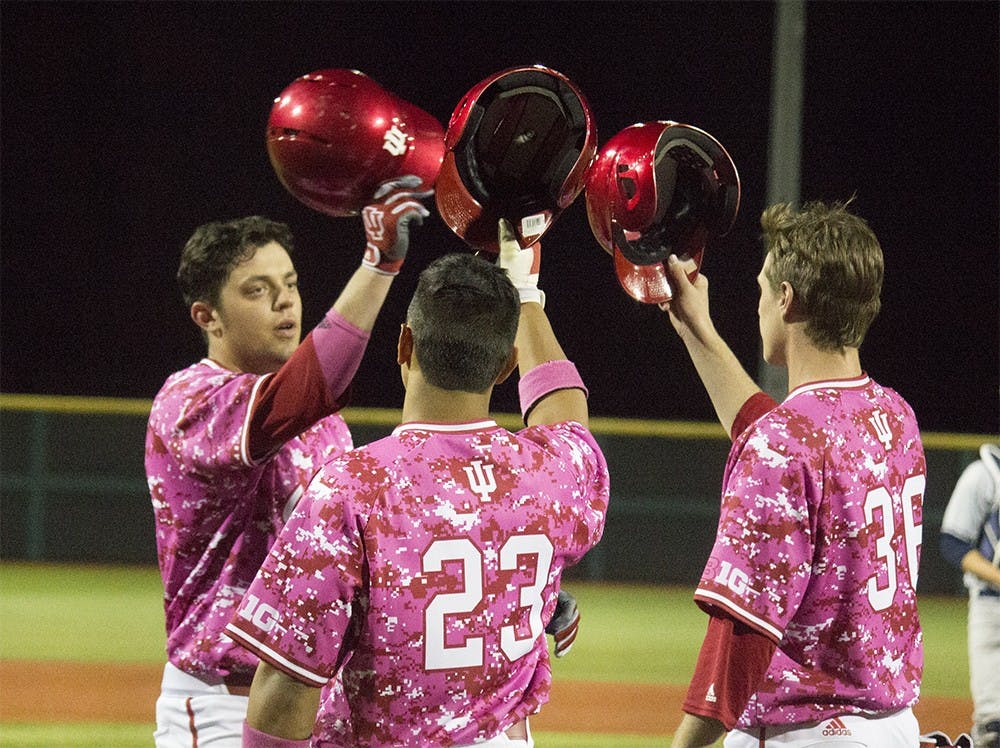 Junior Austin Cangelosi, left, taps helmets with his teammates after scoring his second home run of the night against Butler on Wednesday at Bart Kaufman field. The Hoosiers beat the Bulldogs with a score of 27-1.