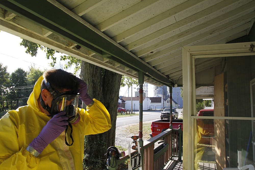 Hoke puts on and adjusts his gas mask straps before entering the home. Often the crew's work days are eight hours long.