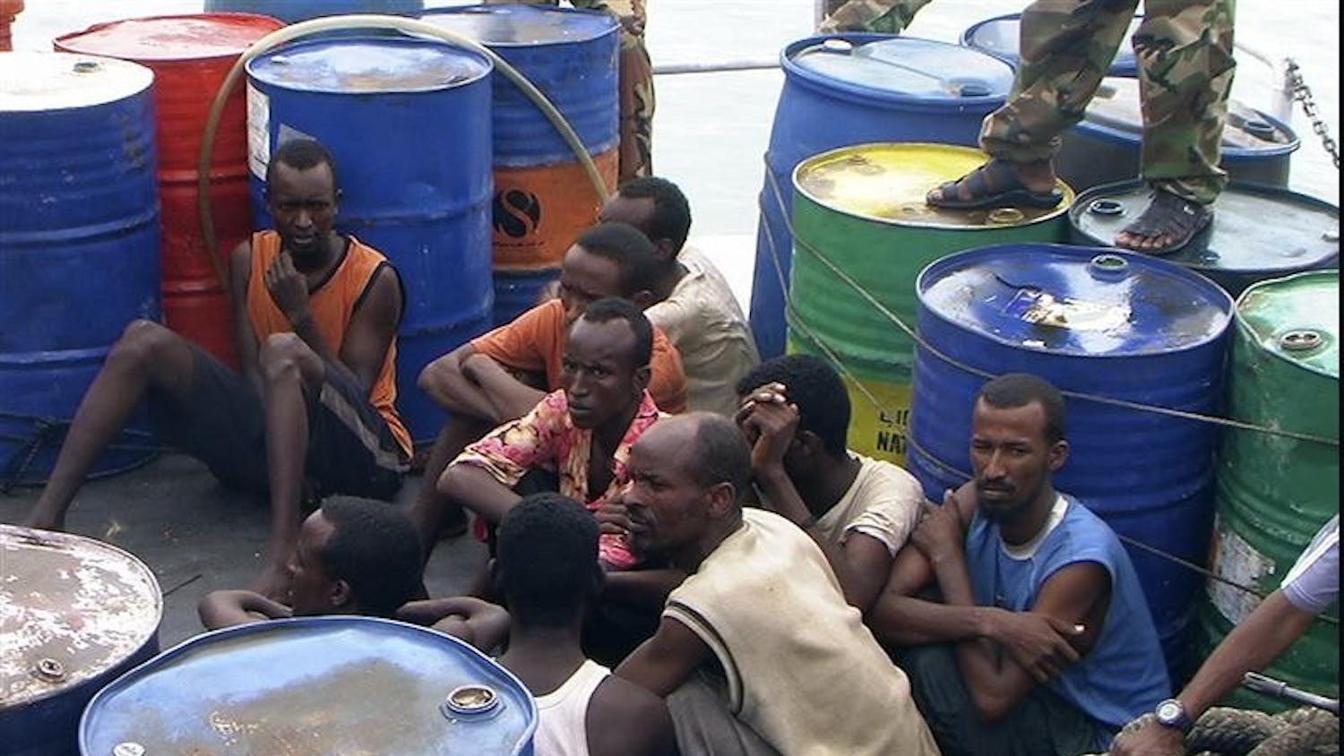 In this Nov. 21, 2008 file photo, Somali pirates held by Puntland police forces, sit in Bassaso, Somalia. They've been described as "noble heros" by sympathetic Somalis, denounced as criminals by critics. But the adjective most used to describe the men holding an American captain off the Horn of Africa is "pirate," a word that conjures images of sword-wielding swashbucklers romanticized by Hollywood. The 21st century reality of ragged Somali fishermen armed with rocket launchers, GPS systems and satellite phones, though, is a far cry from that.