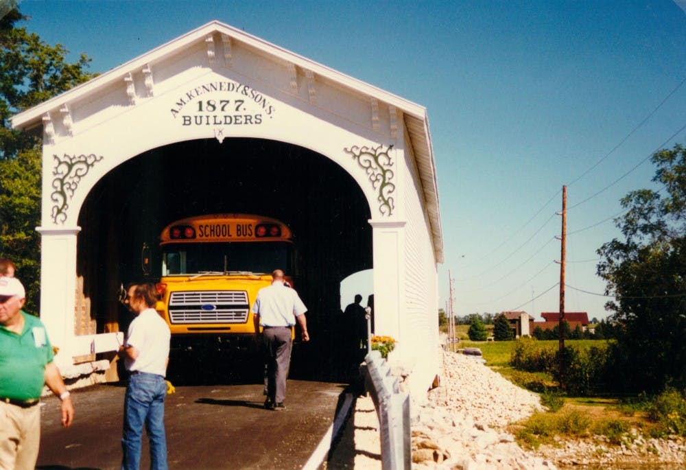 <p>A school bus drives through the Smith Covered Bridge in Rush County, Indiana, after its reopening in 1996. The reconstructed covered bridge coming to Monroe County will look much like the Smith Covered Bridge when finished.&nbsp;</p>