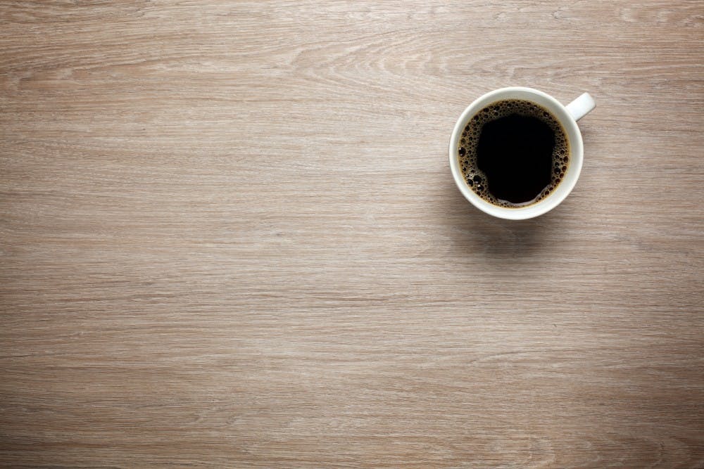 <p>A cup of coffee sits on an office desk.</p>