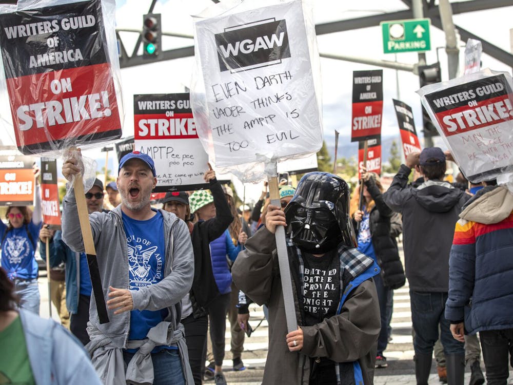 Writers Joe Henderson (left) and Montserrat Luna, wearing a Darth Vader helmet (right) strike with other members of the Writers Guild of Americaon May 4, 2023, in Universal City, California. After an unsuccessful six weeks of negotiations with the Alliance of Motion Picture and Television Producers, members of the Writers Guild decided to go on strike outside of NBC/Universal Studios.