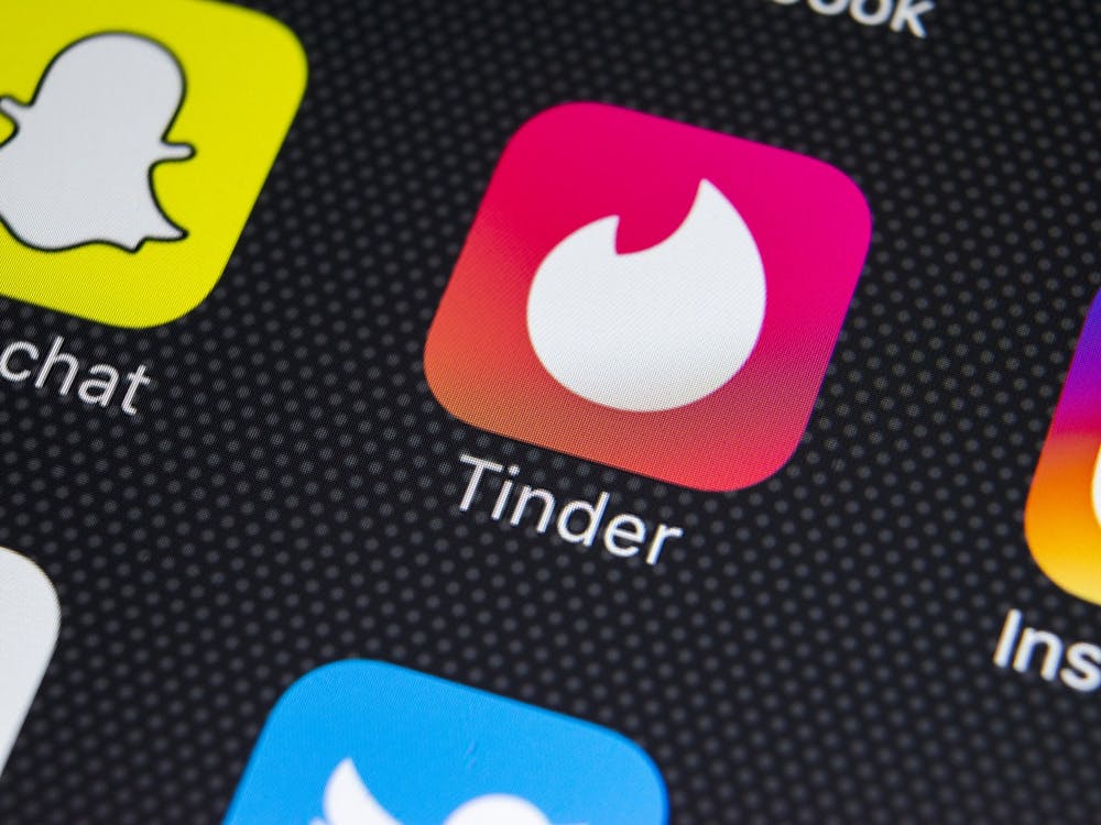 A phone screen shows the dating app Tinder.