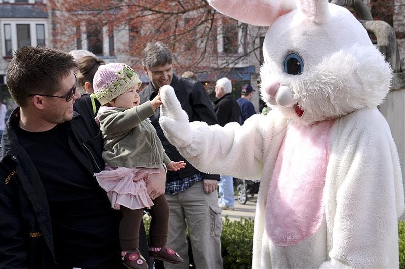 Jason Besecker watches as 1-year old Miya Rose Besecker gives the Easter Bunny a high-five during the Annual Downtown Easter Egg Hunt on Saturday morning on the Monroe County Courthouse Lawn.