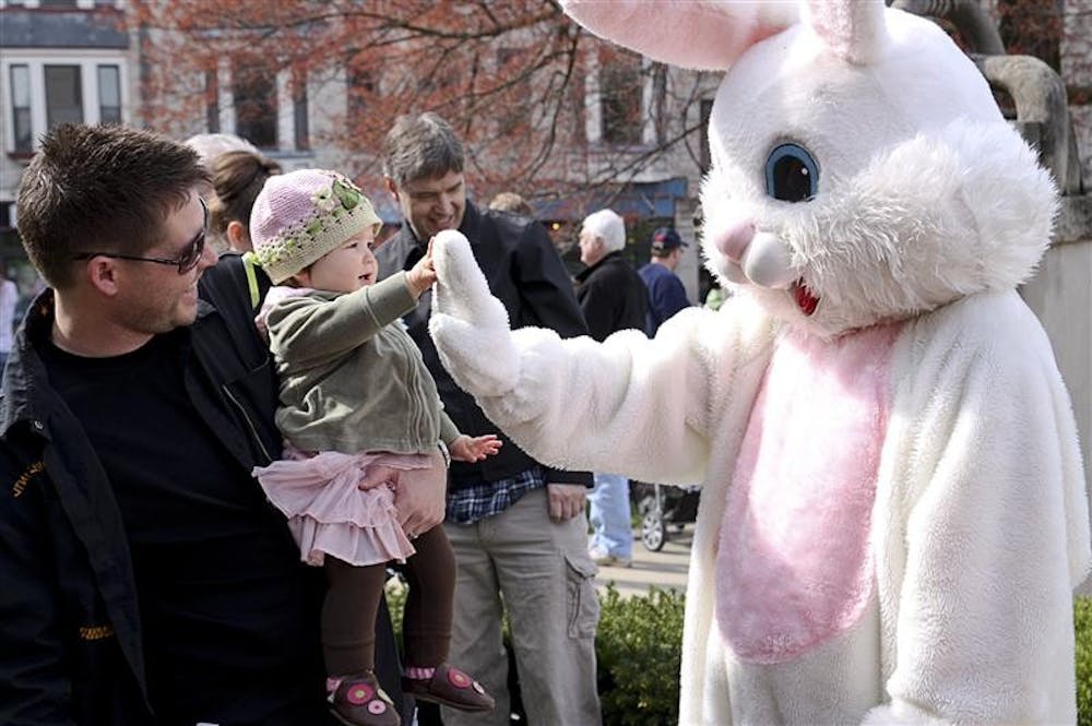 Jason Besecker watches as 1-year old Miya Rose Besecker gives the Easter Bunny a high-five during the Annual Downtown Easter Egg Hunt on Saturday morning on the Monroe County Courthouse Lawn.