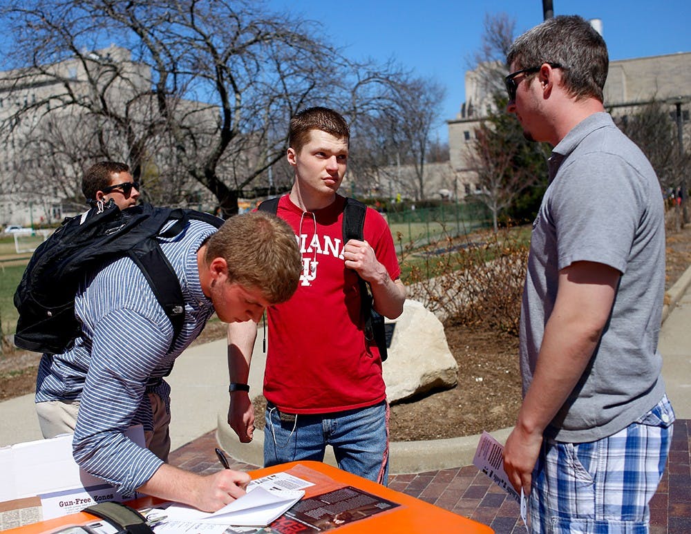 Freshman Collin Evans, left, signs up his name on the sign up sheet and senior Caleb Sperry listens about the purpose of the Empty Holster Protest from sophomore Miles Vining Wednesday right next to Wells Library. Students for Concealed on Campus at Indiana University was established in 2010 to spread awareness of the importance of freedom to carry handguns on the campus to protect themselves. The members protested by wearing a empty holster. The protest will be held until Apr.3. 