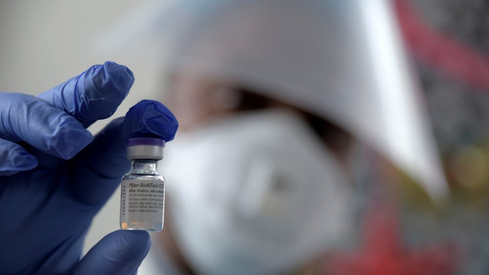 Pharmacist Basil Ebekonye examines a vial containing the Pfizer coronavirus vaccine Dec. 23 in Baltimore, Maryland.  