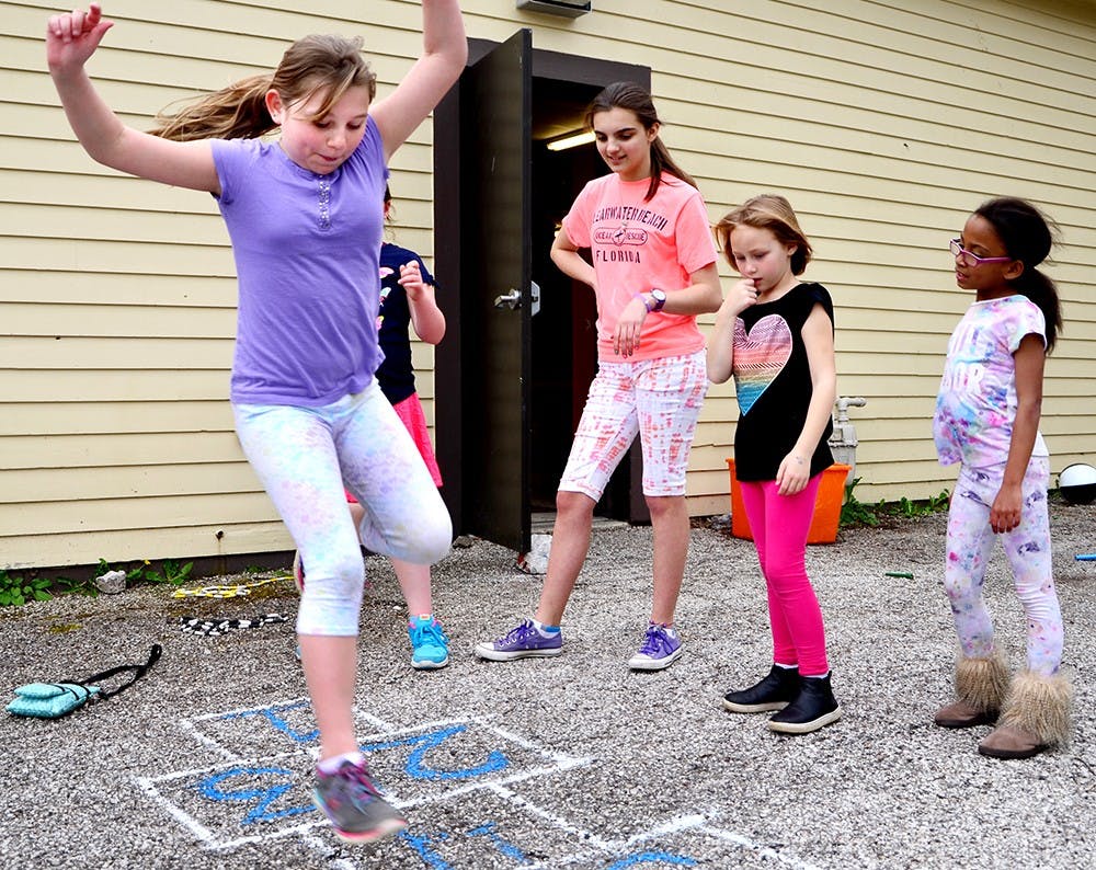 Autumn King, left, 8, plays a hopscotch game with her friends Wednesday at the backyard of Girls Inc. The organization is a local girl supporting place which providesa safe place for games and sports as parts of after school programs. It is partnering with pearls to help low income neighborhood. 