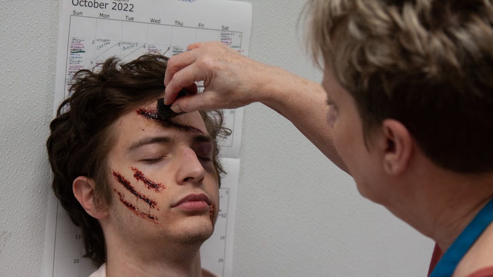 An Indy Scream Park actor sits as head makeup artist Jodi Morgan creates a gory look using Fresh Scab on the evening of Oct.23, 2022. The Park&#x27;s makeup artists use an array of different products, including Fresh Scab, in order to give actors a more realistic appearance.﻿