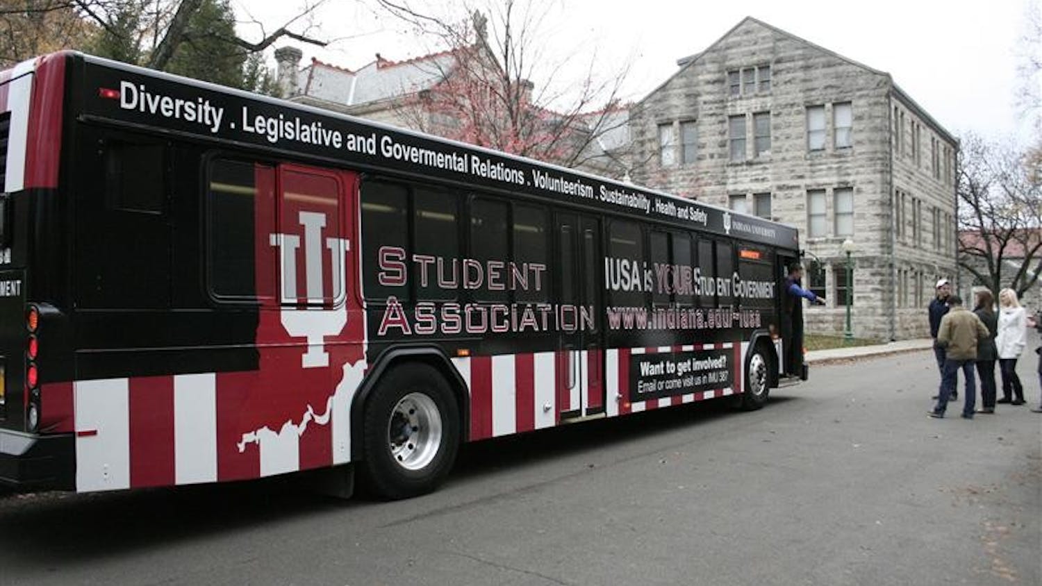 IU Student Association vice president Dan Sloat walks off a newly "wrapped" IUSA bus Sunday behind the IMU. The bus will be launched this week and will have the IUSA advertisement for 12 months.