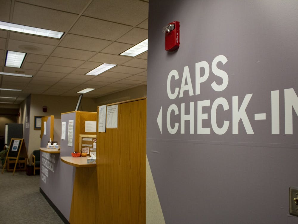 A sign for the Counseling and Psychological Services check-in desk hangs on the wall. In response to IU canceling face-to-face classes and encouraging students to go home, CAPS has moved all appointments to phone and video counseling. 