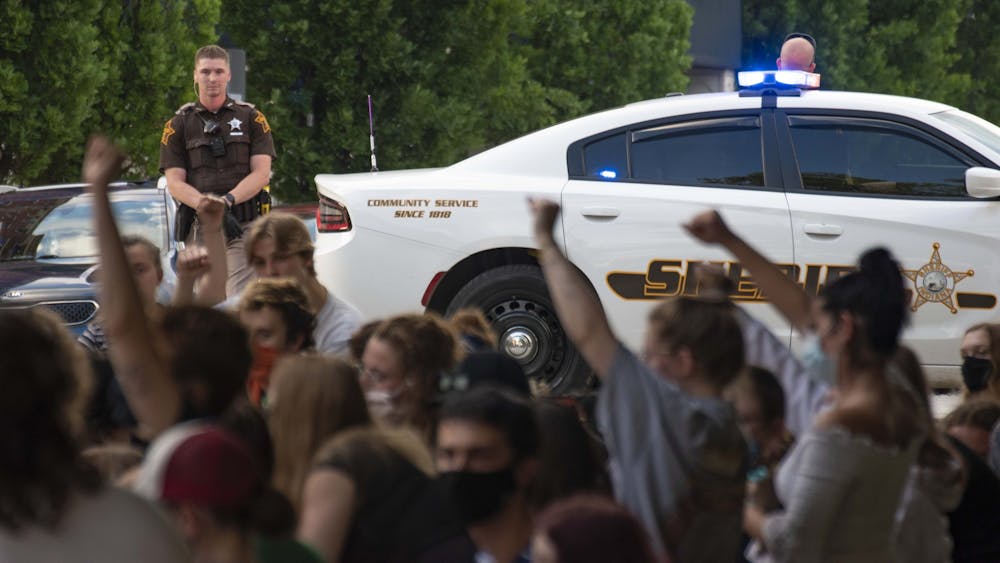 A sheriff’s car blocks traffic during a protest May 29 on North College Avenue outside the Charlotte T. Zietlow Justice Center in Bloomington. Protesters kneeled in silence for 7 minutes, some raised their fists.