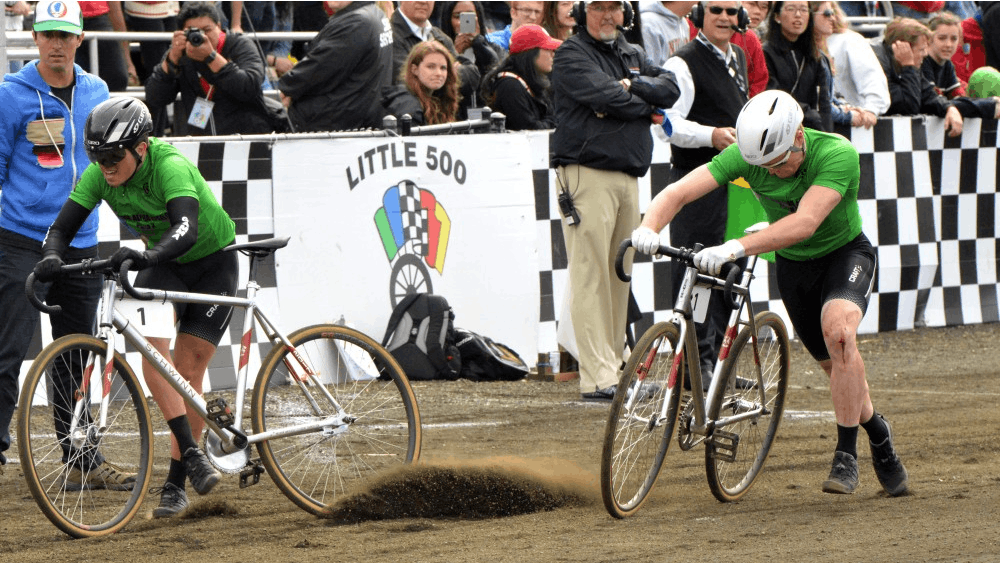Sigma Alpha Epsilon exchanges bikes at the Men's Little 500 in 2017 at Bill Armstrong Stadium. Dirt from the track gets moved by the tire of one of the bikes, because of the dry track. Cyclists may prefer the track to be more wet for an easier and faster ride on the track. &nbsp;