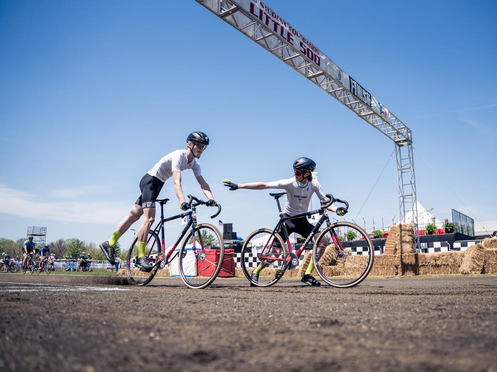Two riders from Grey Goat Cycling practice an exchange before the Men&#x27;s Little 500 on April 23, 2022, at Bill Armstrong Stadium. Great Goat finished fourth.