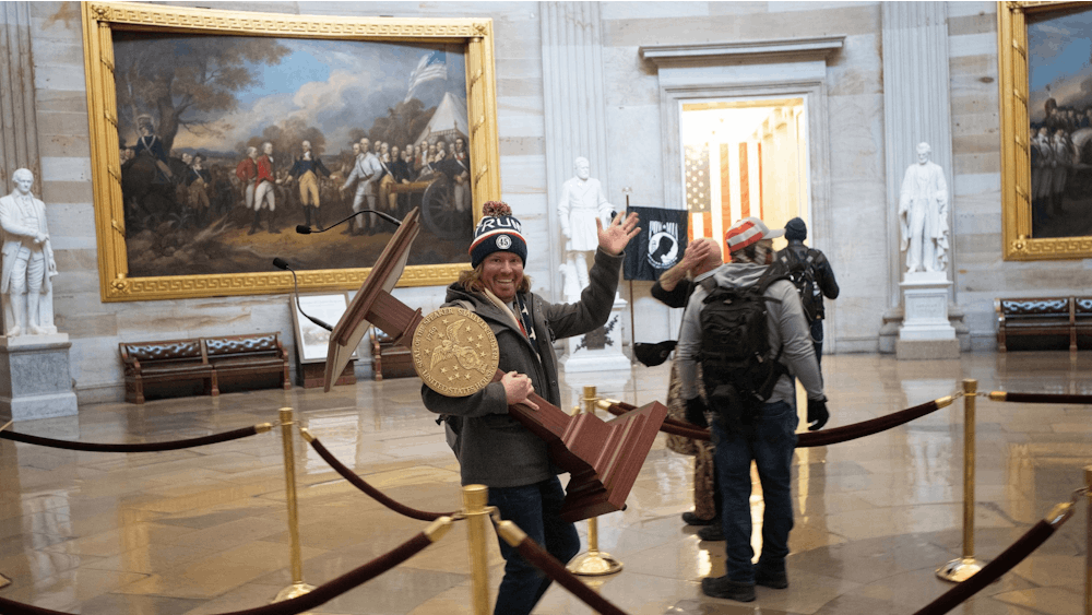 A Trump supporter carries the lectern of U.S. Speaker of the House Nancy Pelosi through the Rotunda of the U.S. Capitol Building after a pro-Trump mob stormed the building on Jan. 6, 2021, in Washington, D.C. Though it has been a year since the insurrection at the Capitol, little has changed since.