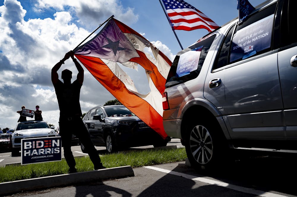 <p>A supporter holds up the flag of Puerto Rico as then-Democratic Presidential candidate and former U.S. Vice President Joe Biden delivers remarks Oct. 29, 2020, at a drive-in event in Coconut Creek, Florida. </p>