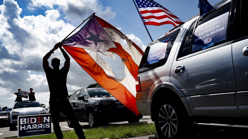 A supporter holds up the flag of Puerto Rico as then-Democratic Presidential candidate and former U.S. Vice President Joe Biden delivers remarks Oct. 29, 2020, at a drive-in event in Coconut Creek, Florida. 