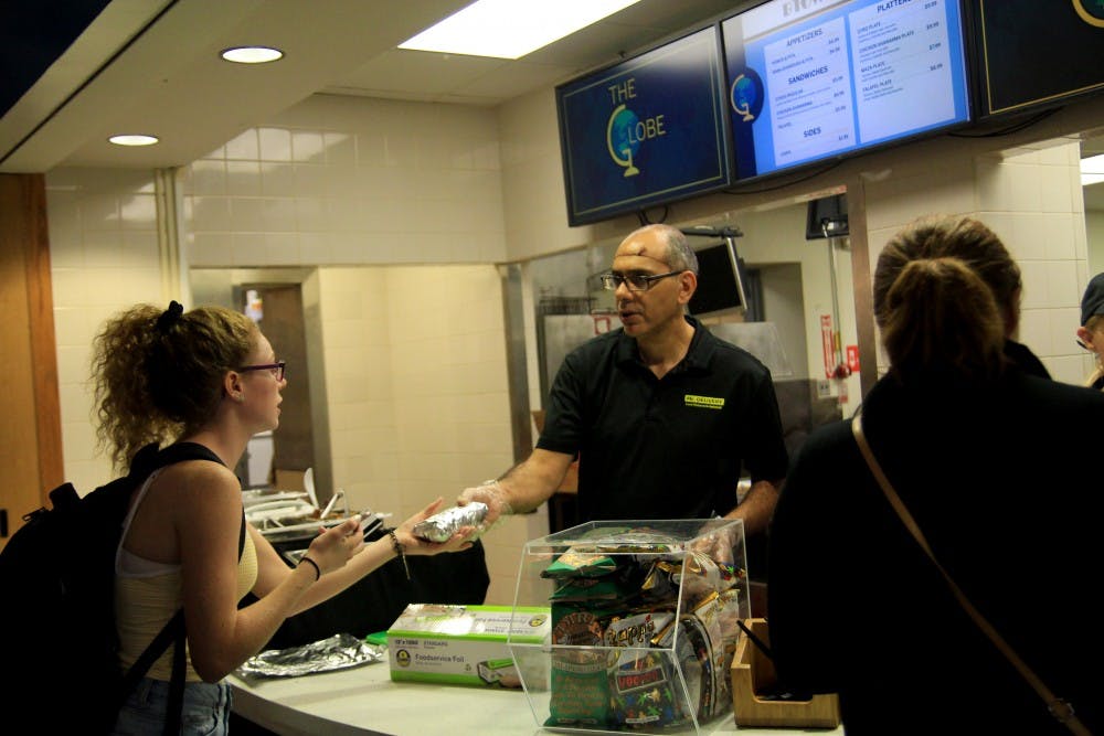 A worker hands food from Btown Gyros to a student at the Globe in the Indiana Memorial Union. Starting this week, the Globe in the IMU serves food from different restaurants around Bloomington.&nbsp;