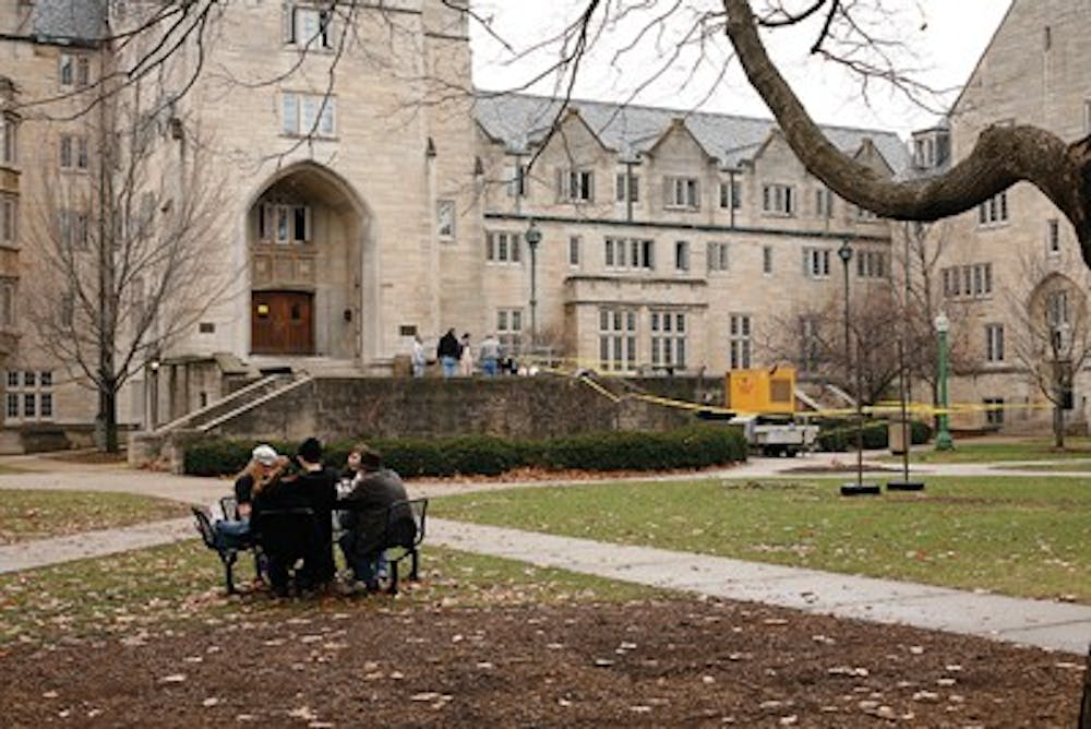 Students sit outside Collins LLC on Sunday afternoon during the power outage.