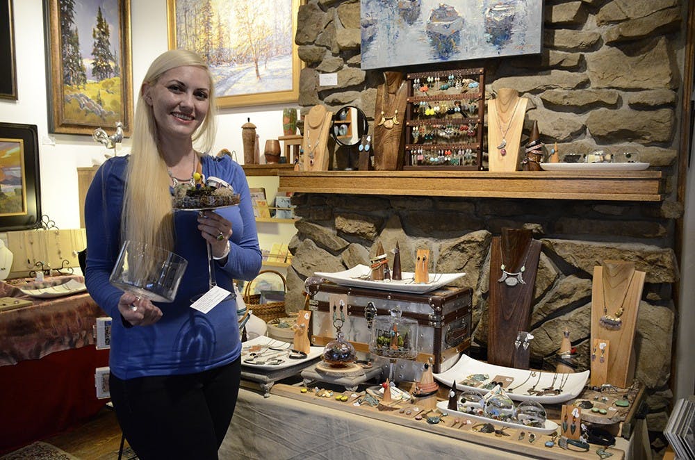 Lori McDonald holds her work and stands by her display table at the Venue Fine Art & Gifts on Tuesday. The small green spheres are bits of marimo moss, which thrive in ponds and aquariums and can move from section to section in the piece. 