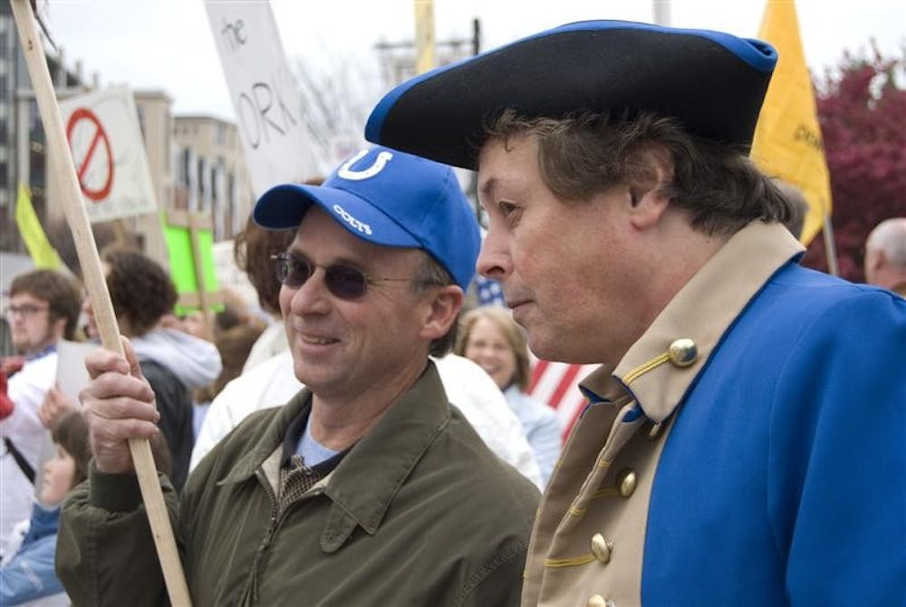 Bloomington resident Mark Walcott talks with fellow resident Randy Carmichael, who is dressed as a revolutionary officer, during a "tea party" protest outside City Hall on Wednesday evening. When asked why he was dressed as a revolutionary, Carmichael responded, "If something's not done, [revolution] is what we're gonna wind up back at. If we all voted Libertarian, we wouldn't be here today."