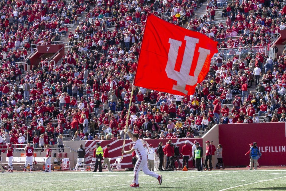 <p>Gavin Schmuckler runs the IU flag across the field Oct. 13, 2018, at Memorial Stadium. IU swim and dive signee Emily Weiss became the 11th swimmer in Indiana history to ever win four state championships Feb. 9.&nbsp;</p>