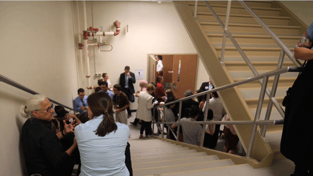 People attending the School of Public and Environmental Affairs networking event in Franklin Hall sit and stand in the stairwell due to a tornado warning. The event was taking place in Presidents Hall, which is lined with large windows. 
