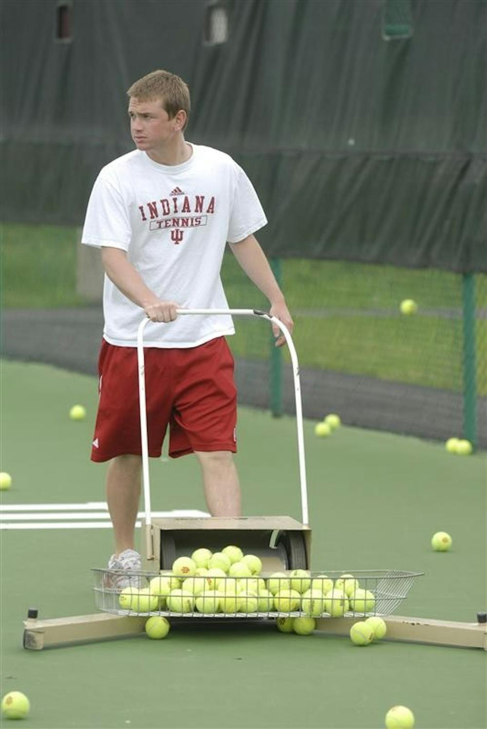 Senior Todd Reed, a four–year manager of the men's tennis team, collects tennis balls during practice Tuesday at the IU Tennis Center. Reed and his brother Scott, a 1997 graduate, both managed for the men's tennis team during their four years at IU.