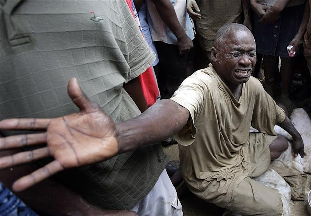 GRIEF – Frantz Samedi weeps over the body of his five year-old daughter, Tamasha Jean, (obscured by him) who was swept away by flooding caused by Hurricane Ike on Sunday in Cabaret, Haiti.