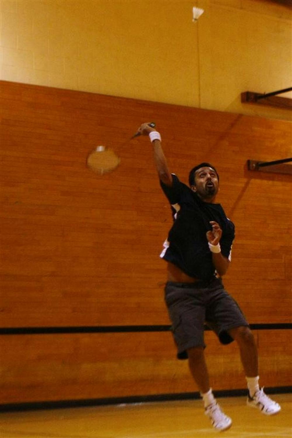 Faculty member Sandeep Chandukala returns the birdie with an overhead shot, while playing in a doubles match against fellow badminton club members during practice on Sunday afternoon at the HPER.