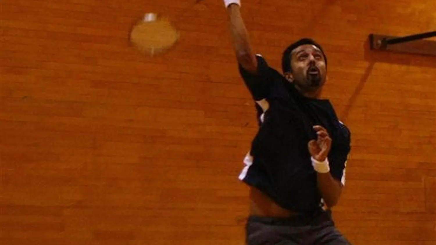 Faculty member Sandeep Chandukala returns the birdie with an overhead shot, while playing in a doubles match against fellow badminton club members during practice on Sunday afternoon at the HPER.