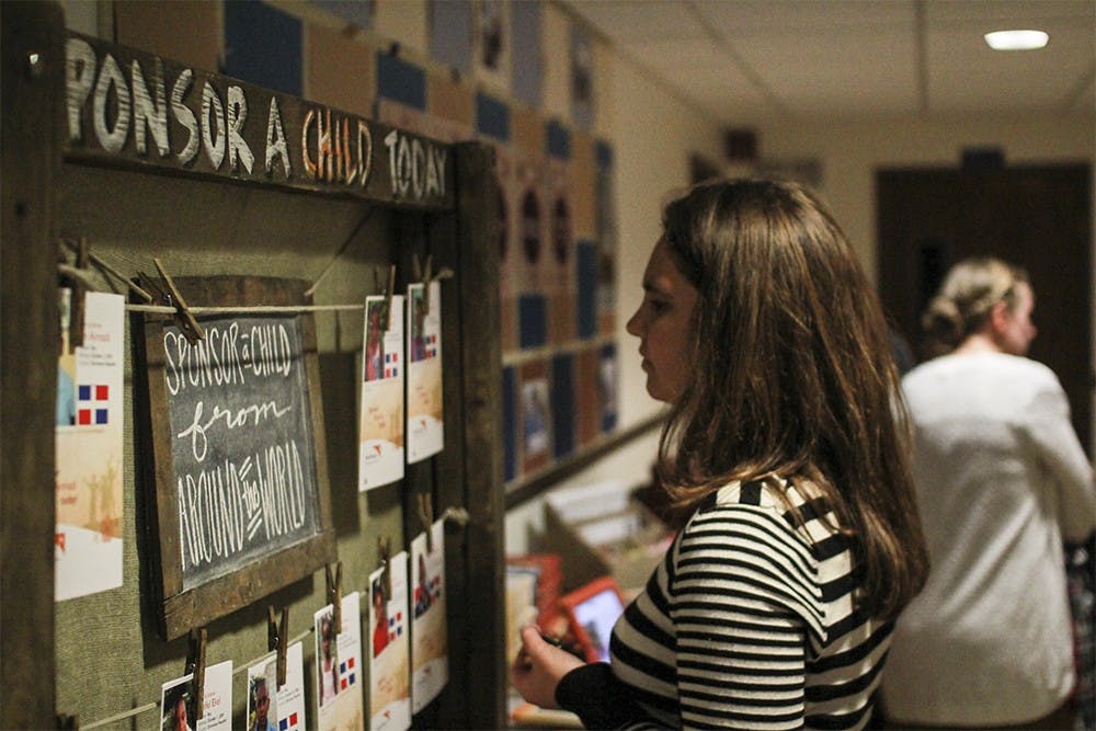 Leslie Tait peruses the board of World Vision children to sponsor last Sunday. Tait, a Bloomington resident, was invited to the exhibit by a friend at the Evangelical Community Church.