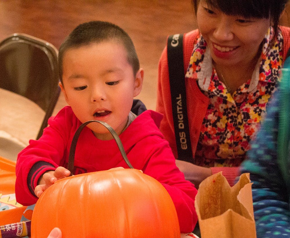 Yoyo Xu picks out candy with his mother Luming after making a monster bookmark at the Mathers Museum's Halloween Family Fun Fest.