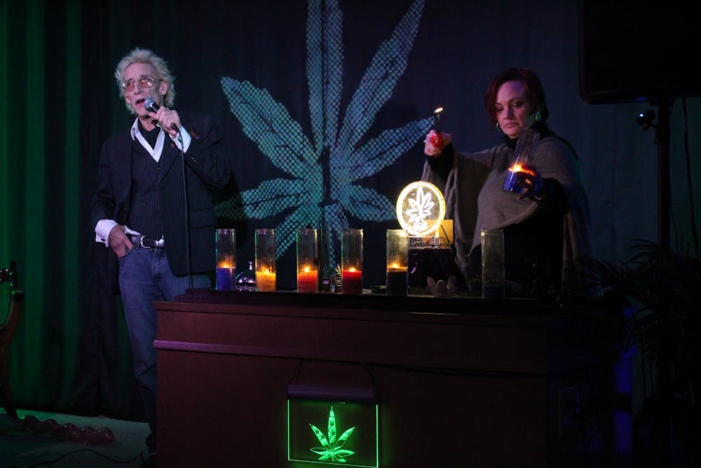 Bill Levin talks about how the candles represent the seven focus areas as a member of the First Church of Cannabis, Roo Gelarden, lights the candles. The candles represent the following: live, love, laugh, create, grow and teach.