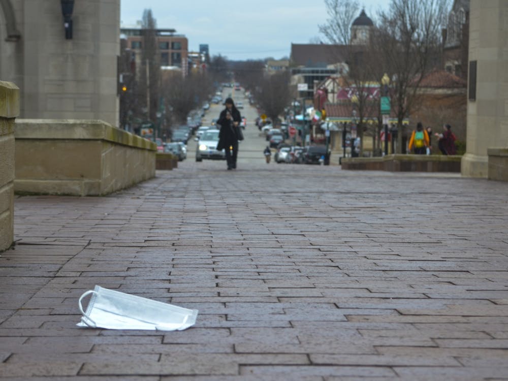 A surgical mask rests on the ground March 12 in front of Sample Gates. IU is asking that as few students be on campus as possible during the upcoming winter intersession due to the coronavirus. 