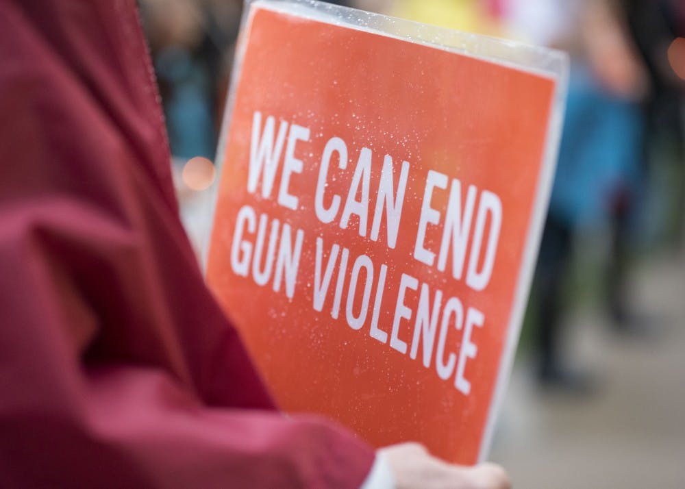 <p>Ann Edmonds holds a sign at the Sunday vigil honoring victims of the Las Vegas shooting. The signs were distributed by Moms Demand Action, a group advocating stricter gun laws.</p>