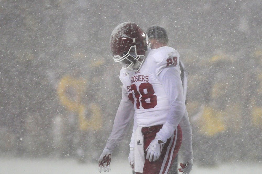 Freshman defensive back A’Shon Riggins walks off a snow-covered Michigan Stadium field near the end of the fourth quarter. IU lost to Michigan 20-10.